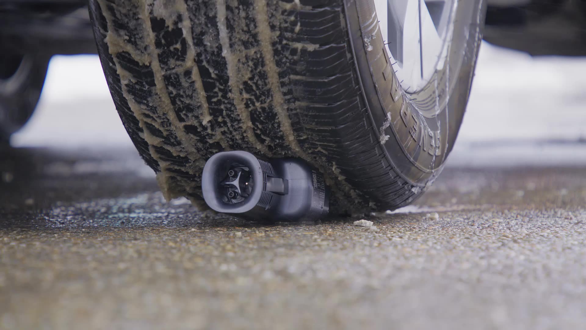 The new Ford Fast Charging Adapter is shown intact beneath a vehicle tire.
